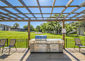 Thumbnail 7 of 15 - a patio with a grill and chairs under a roof