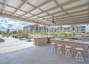 Thumbnail 35 of 44 - A patio with a bar and stools under a white canopy.