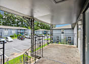 Thumbnail 8 of 37 - A view from a covered patio looking out to a parking lot and apartment buildings.