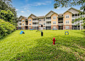 Thumbnail 19 of 31 - A red fire hydrant sits in the middle of a grassy area in front of apartment buildings.