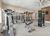 Thumbnail 31 of 44 - A spacious gym with a variety of equipment including treadmills, weights, and a television.