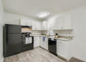 Thumbnail 1 of 27 - A kitchen with black appliances and white cabinets.