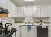 Thumbnail 2 of 27 - A kitchen with white cabinets and a black stove top.