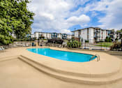 Thumbnail 15 of 27 - A swimming pool surrounded by a concrete deck and a fence.