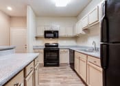 Thumbnail 12 of 37 - a kitchen with light wood colored cabinets and black appliances at Avenues of Kennesaw East & West, Kennesaw, 30144
