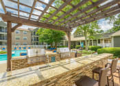 Thumbnail 21 of 37 - a poolside outdoor kitchen featuring 2 grills and a counter at Avenues of Kennesaw East & West, Kennesaw, GA 30144