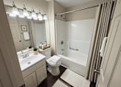 Thumbnail 6 of 18 - A bathroom with a white toilet, sink, and shower.