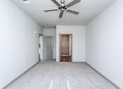 Thumbnail 11 of 27 - a bedroom with white walls and a ceiling fan