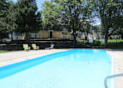 Thumbnail 2 of 30 - A swimming pool surrounded by trees and chairs.
