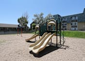 Thumbnail 23 of 30 - A playground with a yellow slide and a green fence.