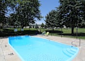 Thumbnail 1 of 30 - A blue swimming pool surrounded by a black fence and trees.