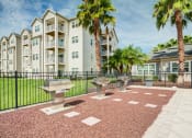 Thumbnail 6 of 25 - a patio with three bbq pits and two palm trees in front of an apartment building  at Century Avenues, Florida, 33813
