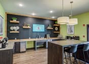 Thumbnail 10 of 29 - a kitchen with a large island with a breakfast bar and a tv on the wall at Century Belmont Station, Louisville, KY
