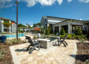 Thumbnail 13 of 30 - a patio with chairs and a table next to a swimming pool at Century Dunes Apartments, Deland, FL, 32724