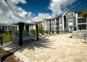 Thumbnail 18 of 30 - a courtyard with benches and a pool in front of an apartment building at Century Dunes Apartments, Deland, FL, 32724