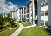 Thumbnail 17 of 30 - an exterior view of an apartment building with grass and trees at Century Dunes Apartments, Florida