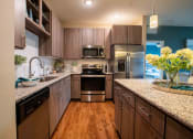 Thumbnail 21 of 30 - a kitchen with wooden cabinets and stainless steel appliances at Century Dunes Apartments, Deland, 32724