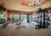 Thumbnail 3 of 30 - a gym with weights and other equipment in a room with windows at Century Dunes Apartments, Deland, FL