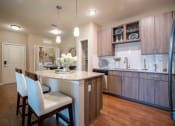 Thumbnail 22 of 30 - a kitchen with a bar and white chairs at Century Dunes Apartments, Deland, Florida