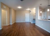 Thumbnail 29 of 30 - an empty living room with wood flooring and a kitchen at Century Dunes Apartments, Florida