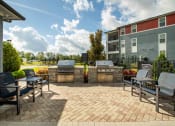 Thumbnail 7 of 30 - a patio with two barbecue grills and chairs on it at Century Dunes Apartments, Deland, FL, 32724