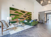 Thumbnail 7 of 32 - a living room with a green couch and a brick wall with moss on it at Century University City, Charlotte, NC