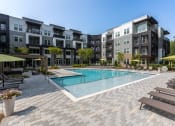 Thumbnail 1 of 32 - a swimming pool with lounge chairs and umbrellas in front of an apartment building at Century University City, Charlotte, 28213