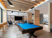 Thumbnail 17 of 28 - a pool table sits in the middle of a room with a tv on the wall  at Century West Pryor, Lee's Summit, Missouri