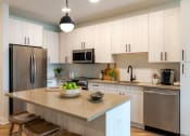 Thumbnail 22 of 28 - a kitchen with white cabinets and a large island with a bowl of fruit on it  at Century West Pryor, Missouri