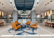 Thumbnail 2 of 28 - a large lobby with orange chairs and tables  at Century West Pryor, Missouri