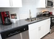 Thumbnail 36 of 62 - A modern kitchen with a black dishwasher and white cabinets.