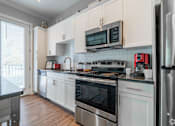Thumbnail 33 of 62 - A kitchen with white cabinets and stainless steel appliances.