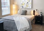 Thumbnail 49 of 62 - A bedroom with a bed, nightstand, and a painting on the wall.