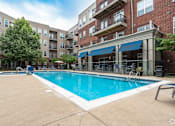 Thumbnail 60 of 62 - A swimming pool in front of a brick building with a blue awning.