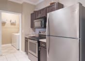 Thumbnail 28 of 29 - a kitchen with stainless steel appliances and black cabinets at Century South Shore, League City, Texas