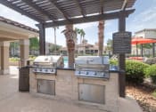 Thumbnail 4 of 29 - an outdoor grill area with two bbq grills under a pergola at Century South Shore, League City, TX