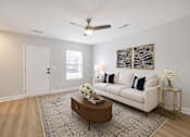 Thumbnail 6 of 21 - A living room with a white couch, a coffee table, and a ceiling fan.