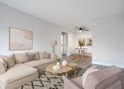 Thumbnail 1 of 18 - A living room with a beige couch, a coffee table, and a painting on the wall.