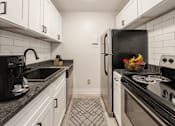 Thumbnail 3 of 18 - A black and white kitchen with a black fridge, black stove, and black countertops.
