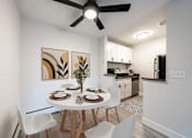 Thumbnail 2 of 18 - A dining room with a white table and chairs, a ceiling fan, and a kitchen area in the background.