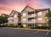 Thumbnail 30 of 31 - A large apartment complex with a parking lot in front.