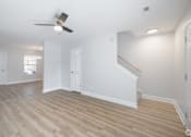Thumbnail 5 of 25 - A room with a ceiling fan and light fixture, wooden flooring, and white walls.