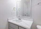 Thumbnail 12 of 25 - A white bathroom with a sink and mirror.