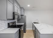 Thumbnail 9 of 25 - A kitchen with a black refrigerator and a white counter top.