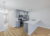 Thumbnail 16 of 25 - A kitchen with a white countertop and a microwave above it.