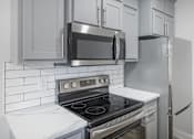 Thumbnail 15 of 25 - A modern kitchen with a stove, microwave, and refrigerator.