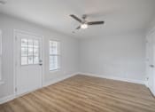 Thumbnail 7 of 25 - A room with a ceiling fan and wooden flooring.