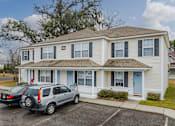 Thumbnail 22 of 25 - A two-story house with a blue door and a car parked in front.