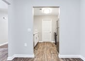 Thumbnail 21 of 81 - a renovated living room and kitchen with white walls and wood floors at Magnolia Place at Stockbridge Apartments, Stockbridge, GA