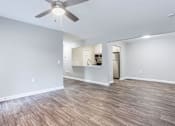 Thumbnail 26 of 81 - an empty living room with a ceiling fan and a kitchen at Magnolia Place at Stockbridge Apartments, Georgia